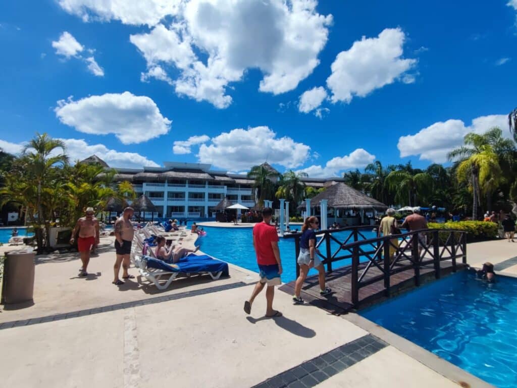 Personas disfrutando de un día soleado en la alberca de un hotel todo incluido. Foto tomada por un cliente feliz de AquíViajeros