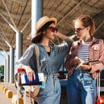 Dos chicas turistas platicando mientras esperan su transporte