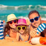 Familia disfrutando de unas vacaciones en la playa con gafas de sol y accesorios de verano.