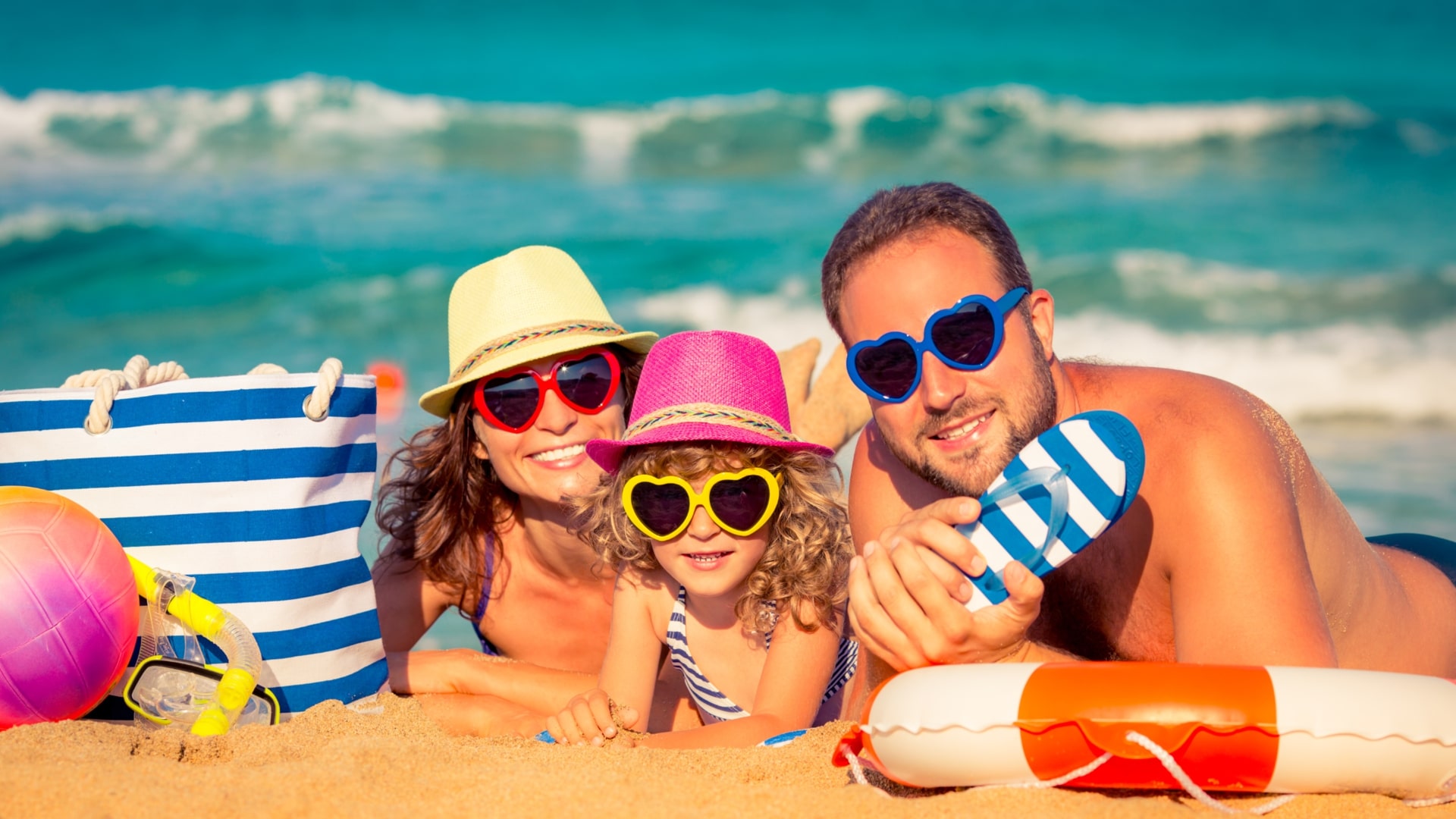 Familia disfrutando de unas vacaciones en la playa con gafas de sol y accesorios de verano.